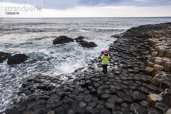 Junge Frau schaut aufs Meer an den Basaltfelsen Giant Causeway  Coleraine  Nordirland  Großbritannien  Europa
