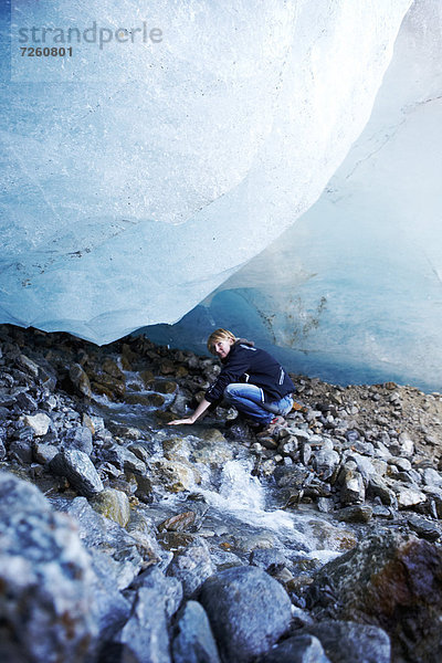 Frau unter Eisblock eines Gletschers  Sustenpass  Schweiz  Europa
