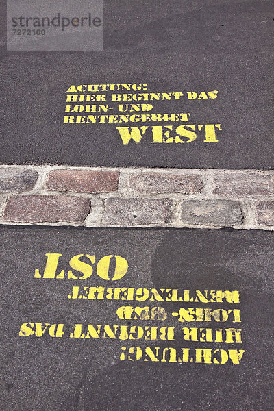 'Gesprühter Schriftzug ''Achtung! Hier beginnt das Lohn- und Rentengebiet Ost  West''  ehemaliger Berliner Mauerverlauf  Potsdamer Platz  Berlin  Deutschland  Europa'