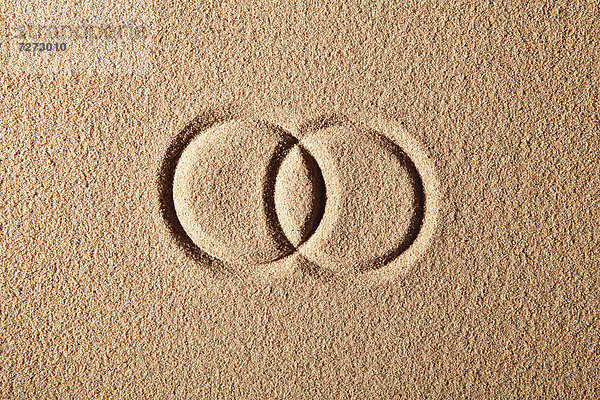 Zwei Ringe  in den Sand gemalt