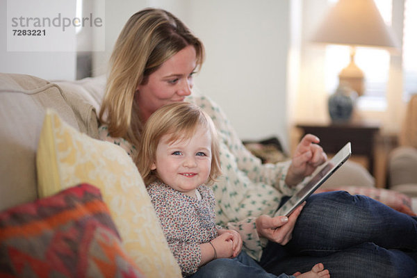 Mutter und Tochter auf Sofa mit digitalem Tablett