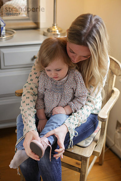Mutter hilft Tochter beim Anziehen des Schuhs
