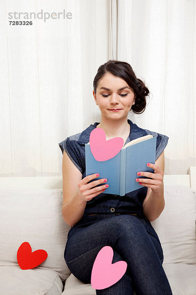 Junge Frau liest Buch mit Herzformen