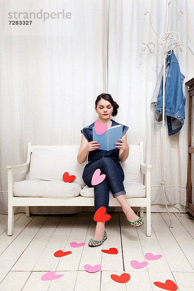 Junge Frau liest Buch mit Herzformen