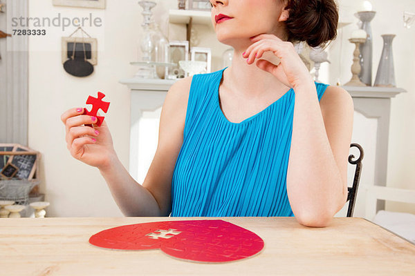 Frau macht herzförmiges Puzzlespiel mit Halteteil