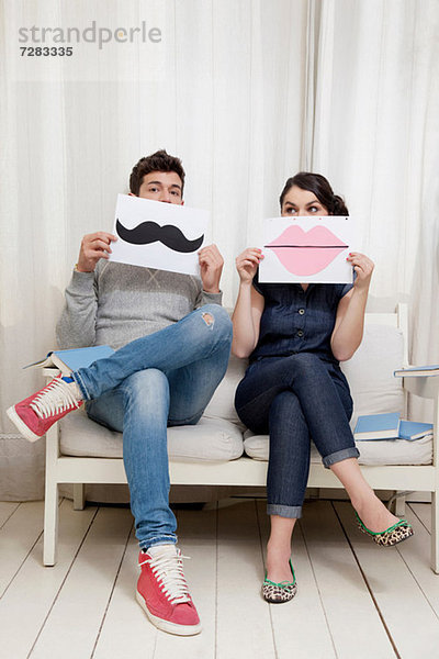 Paar sitzt auf dem Sofa und hält Lippen und Schnurrbart.