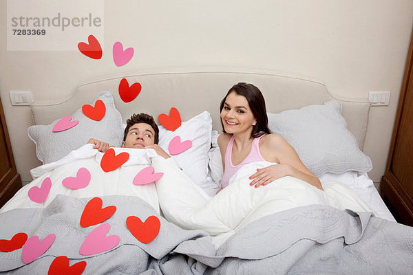 Paar im Bett mit Herzformen auf Bettwäsche
