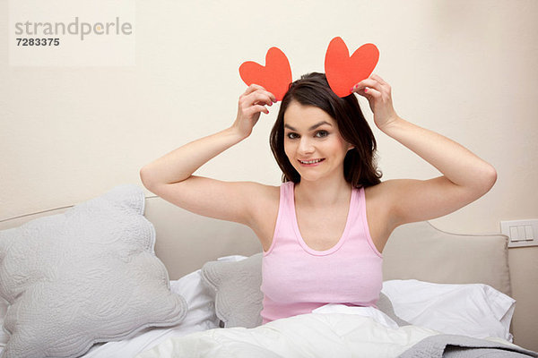 Frau im Bett mit Herzformen als Ohren