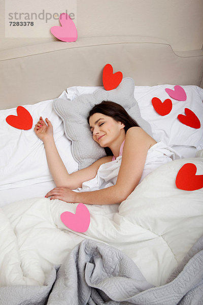 Frau im Bett mit Herzformen auf Bettwäsche