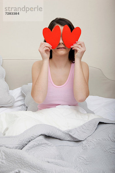 Frau im Bett mit Herzformen über den Augen