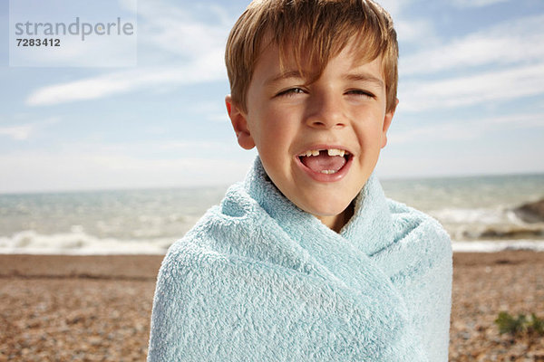 Junge am Strand  in ein Handtuch gewickelt