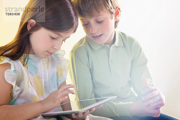 Mädchen und Junge mit digitalem Tablett mit hellem Licht
