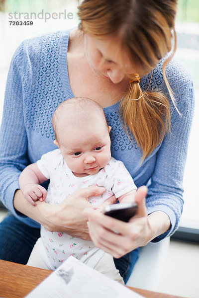 Mutter mit Neugeborenem und Handy