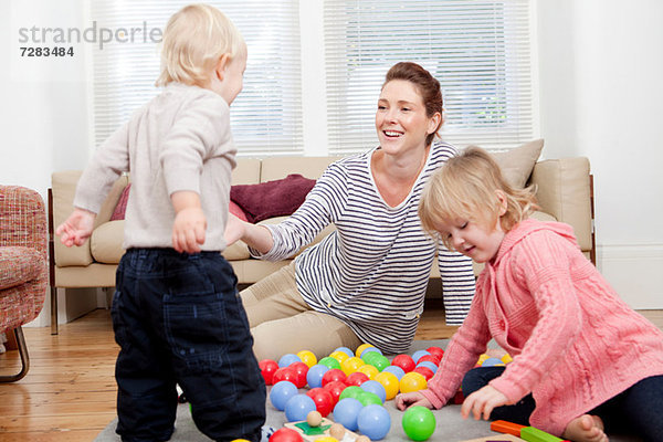 Mutter und Kinder spielen mit Plastikbällen
