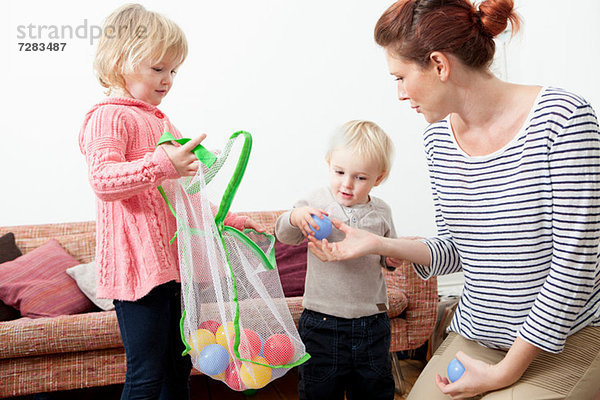 Mutter und Kinder spielen mit Plastikbällen