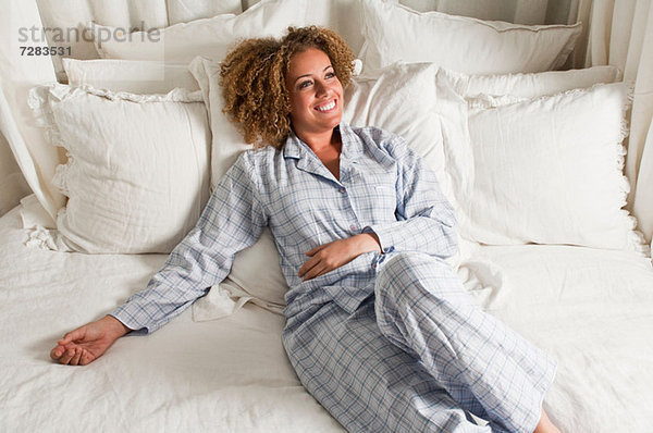 Frau im Schlafanzug im Bett liegend
