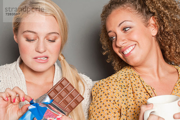 Frau starrt Freund an  der Schokolade hält  Mund