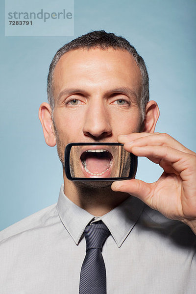 Mann mit Smartphone über dem Mund