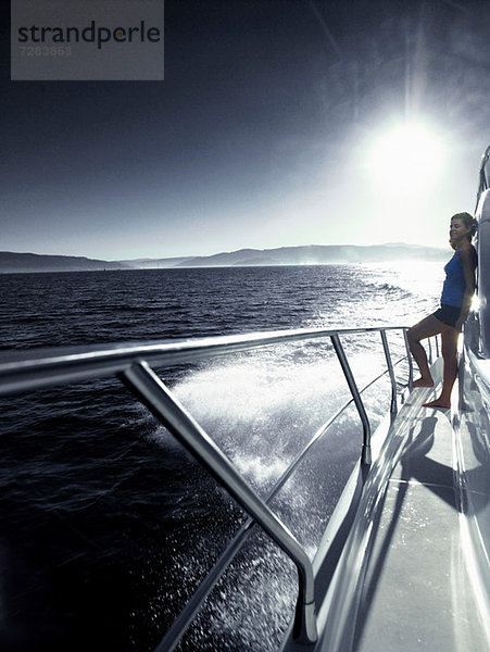 Frau steht allein an Deck der Yacht