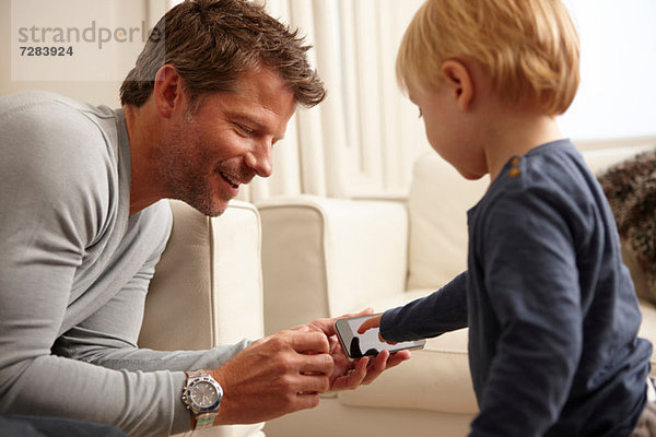 Vater hält Smartphone  Sohn benutzt Touchscreen