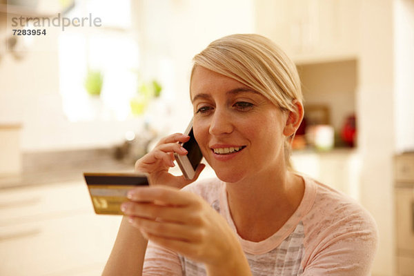 Frau  die ein Smartphone benutzt und eine Kreditkarte besitzt