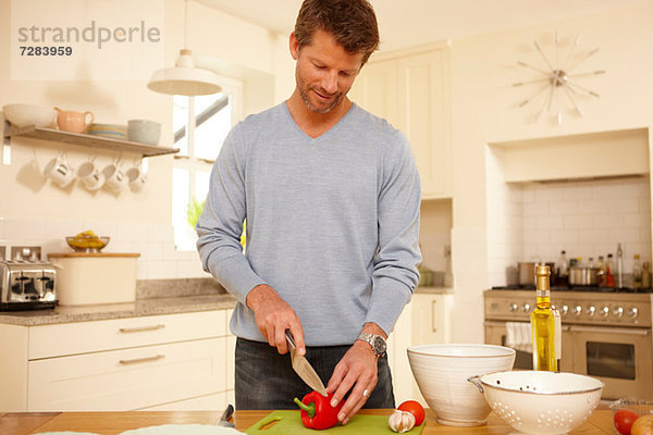 Mann hackt roten Pfeffer in der Küche