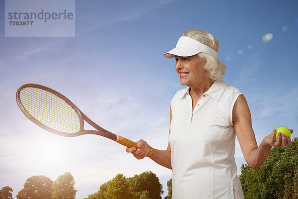 Seniorin mit Tennisschläger und Ball