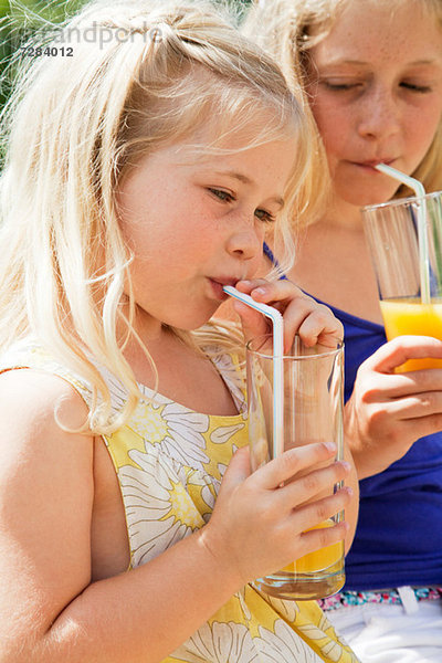Zwei Mädchen trinken Orangensaft