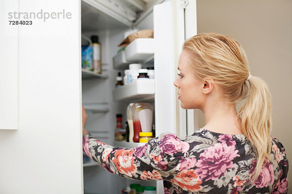 Junge Frau sucht im Kühlschrank