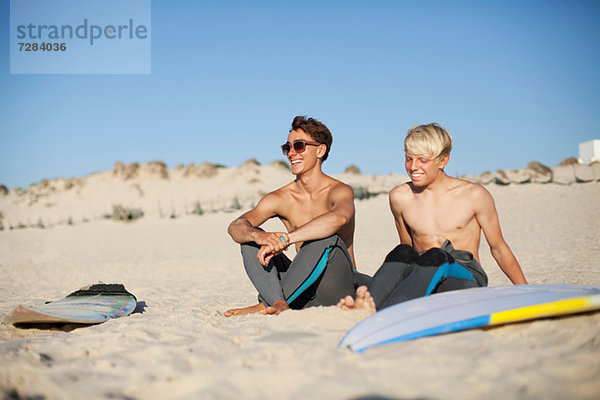 Zwei junge Surfer am Strand sitzend