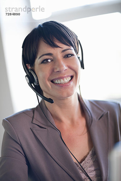 Geschäftsfrau mit Headset am Schreibtisch