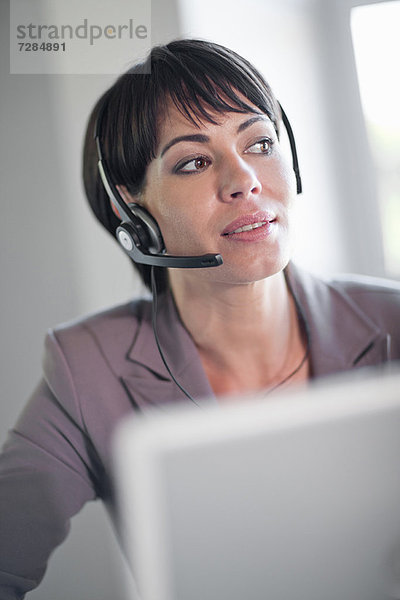 Geschäftsfrau mit Headset am Schreibtisch