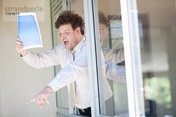 Geschäftsmann schreit aus dem Bürofenster
