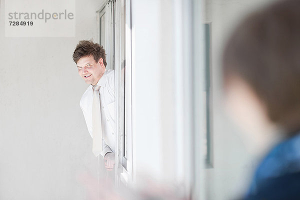 Geschäftsmann lehnt sich aus dem Fenster