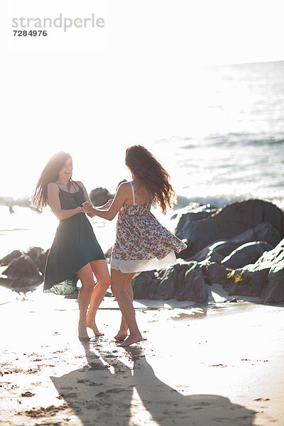 Frauen tanzen zusammen am Strand