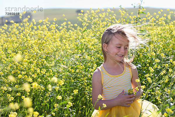 Lächelndes Mädchen spielt im Blumenfeld