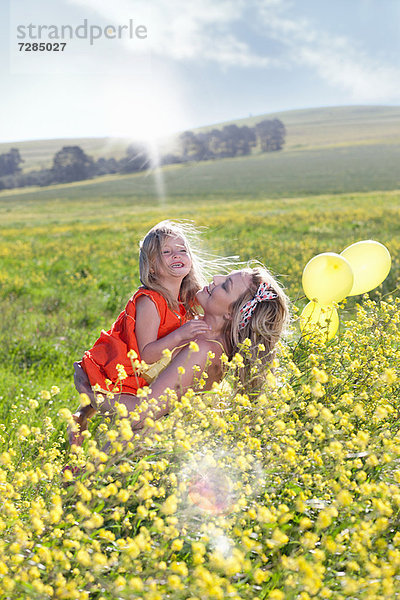 Schwestern spielen im Blumenfeld