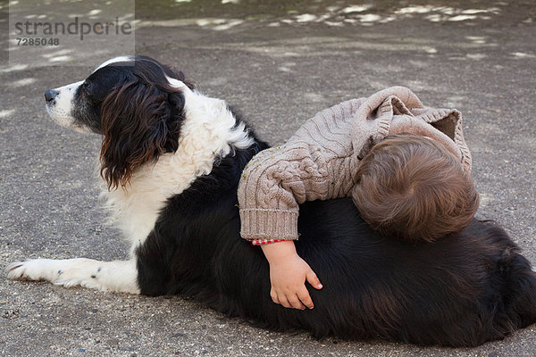 Kleinkind Junge umarmt Hund im Freien