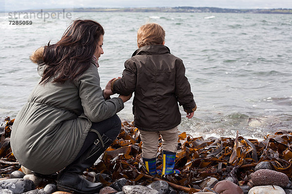 Mutter und Sohn spielen am Felsenstrand