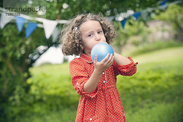 Mädchen beim Aufblasen des Ballons im Freien