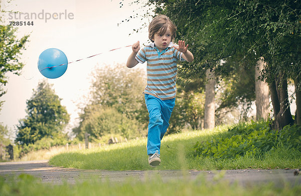 Junge läuft mit Ballon im Freien