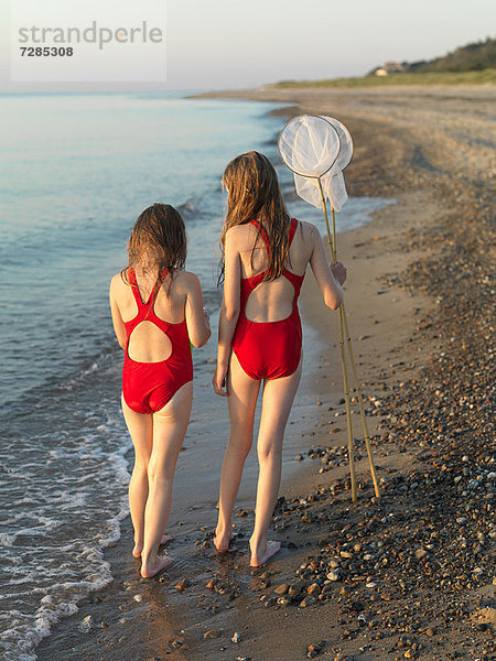 Mädchen  die am felsigen Strand spazieren gehen