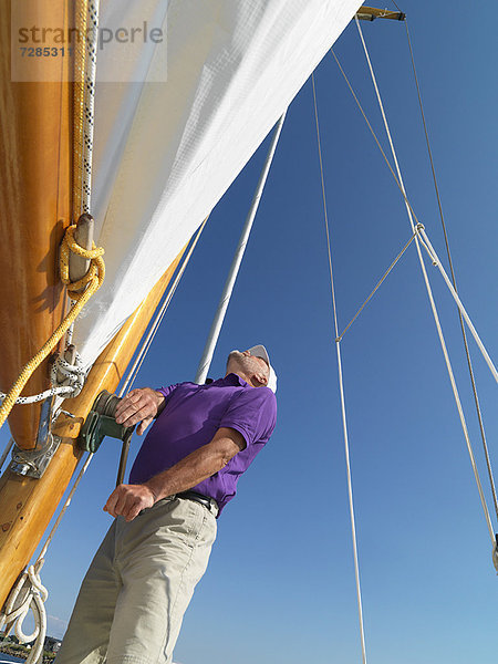 Mann beim Einstellen der Takelage auf dem Segelboot