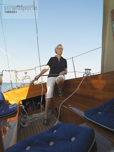 Ältere Frau steuert Segelboot
