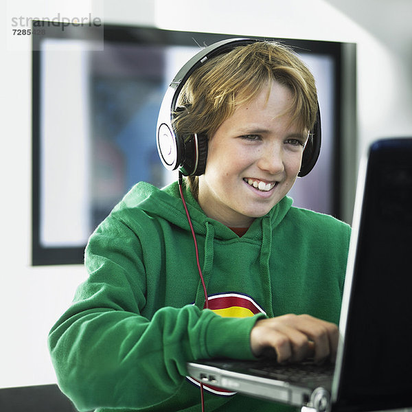 Junge mit Kopfhörer am Laptop