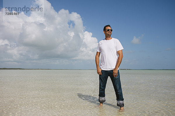 Mann steht im Wasser am tropischen Strand