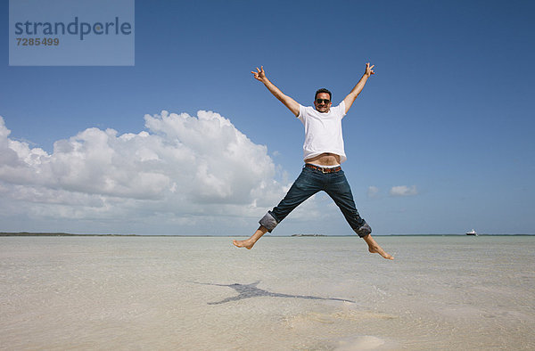 Mann beim Springen im Wasser am tropischen Strand