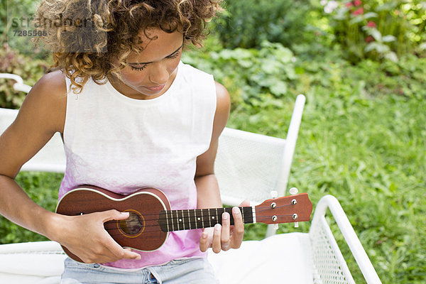 Frau spielt Ukulelele im Hinterhof