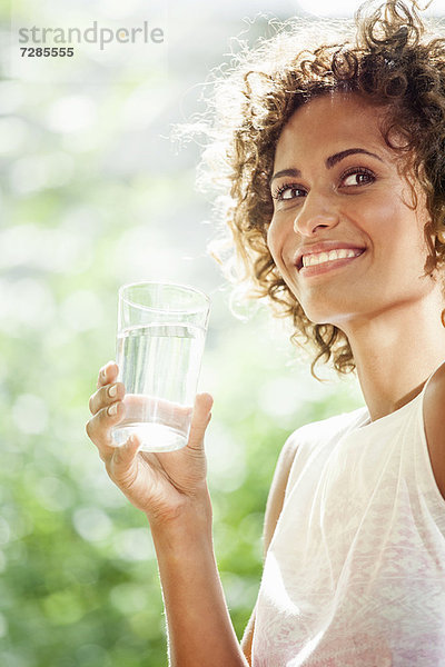 Lächelnde Frau trinkt ein Glas Wasser