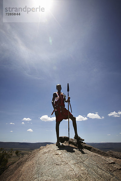 Maasai-Mann auf dem Felsen stehend